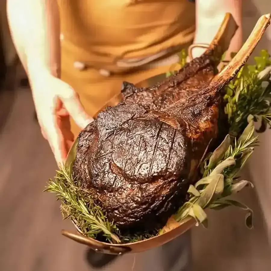 Private chef presenting a tomahawk steak at a Las Vegas bachelor party steakhouse dinner