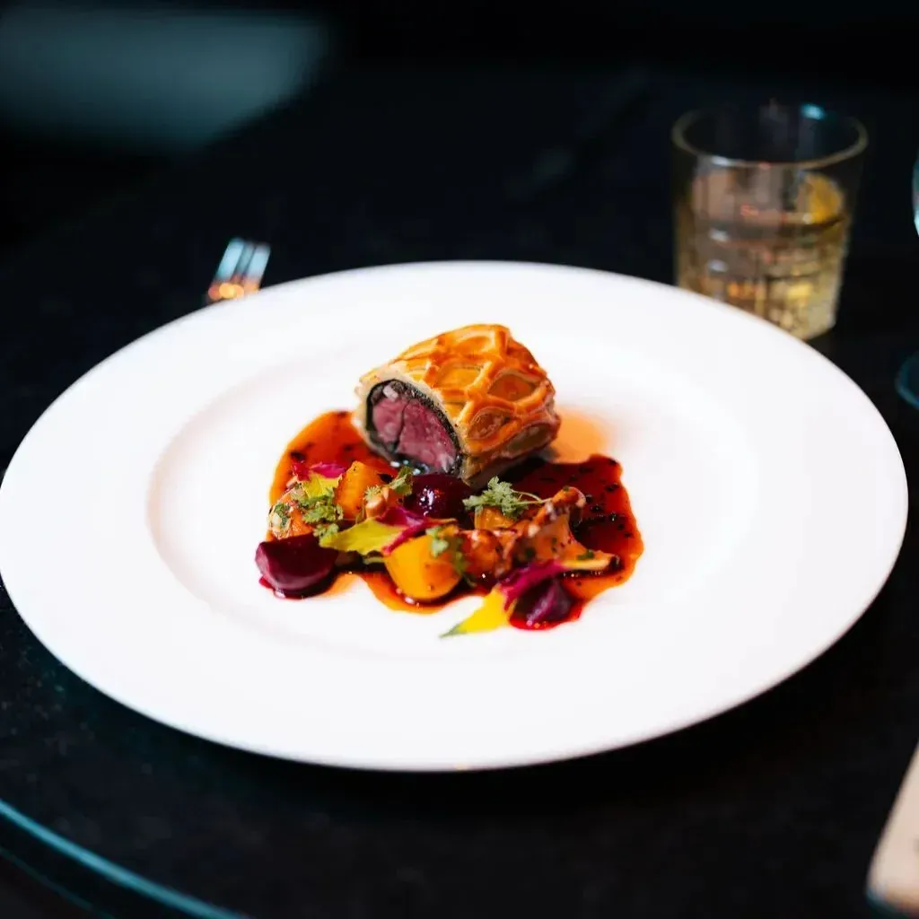 Duck Wellington plated with seasonal root vegetables and jus by a Las Vegas private chef