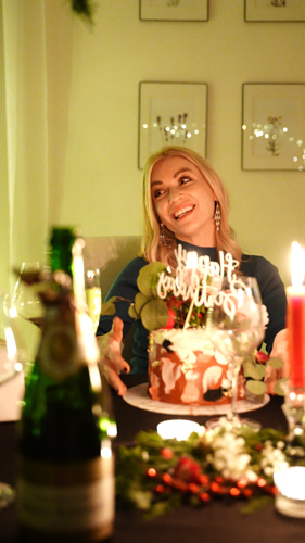 Guest smiling with a decorated celebration cake at a candlelit private chef birthday dinner in Las Vegas