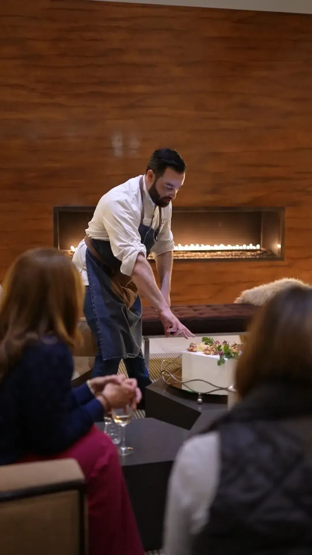 Private chef presenting a canape course to seated guests beside a fireplace at a Las Vegas private dining experience