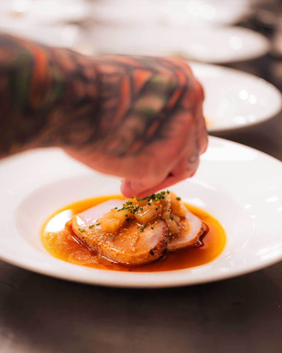 Chef plating seared pork tenderloin with apple mostarda, chives and pan jus at a Las Vegas private chef dinner